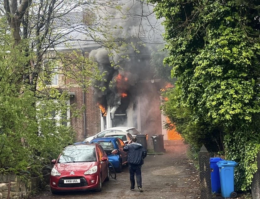 House in flames as man stands outside on the phone