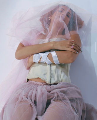 A professional photo with a woman lying down with a veil on and a bandage on her arm