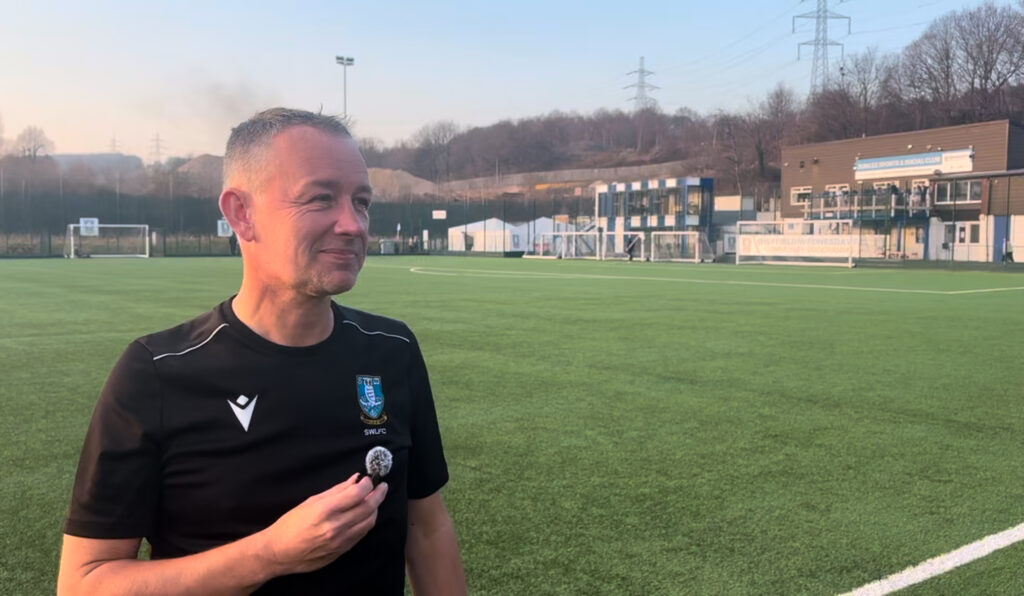 The Sheffield Wednesday manager stands next to the pitch, preparing to be interviewed.