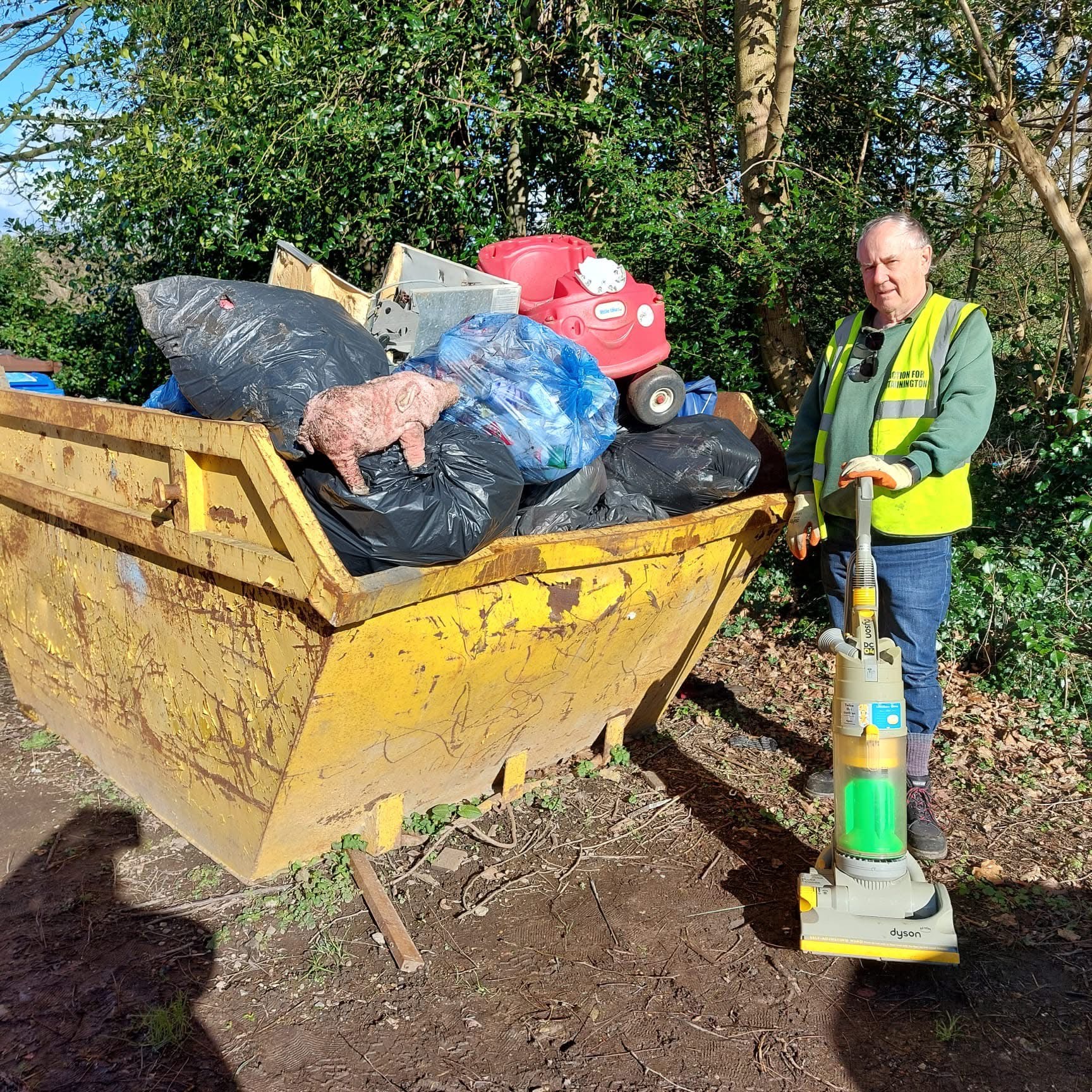 A male volunteer stood next to a full skip