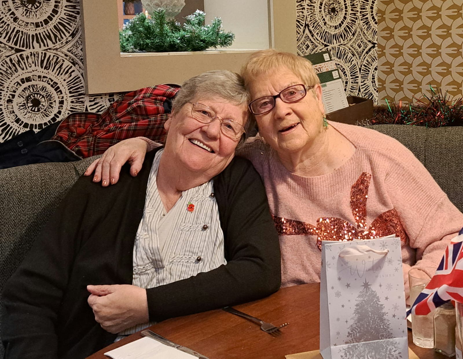 A picture of two elderly women hugging at a Christmas themed Friendship Lunch held in South Yorkshire