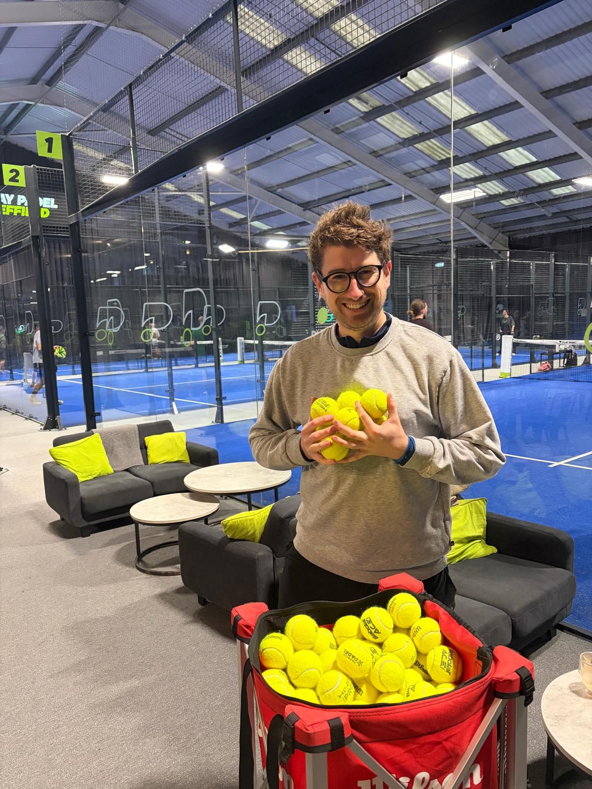 Man stands by padel courts with a handful of balls