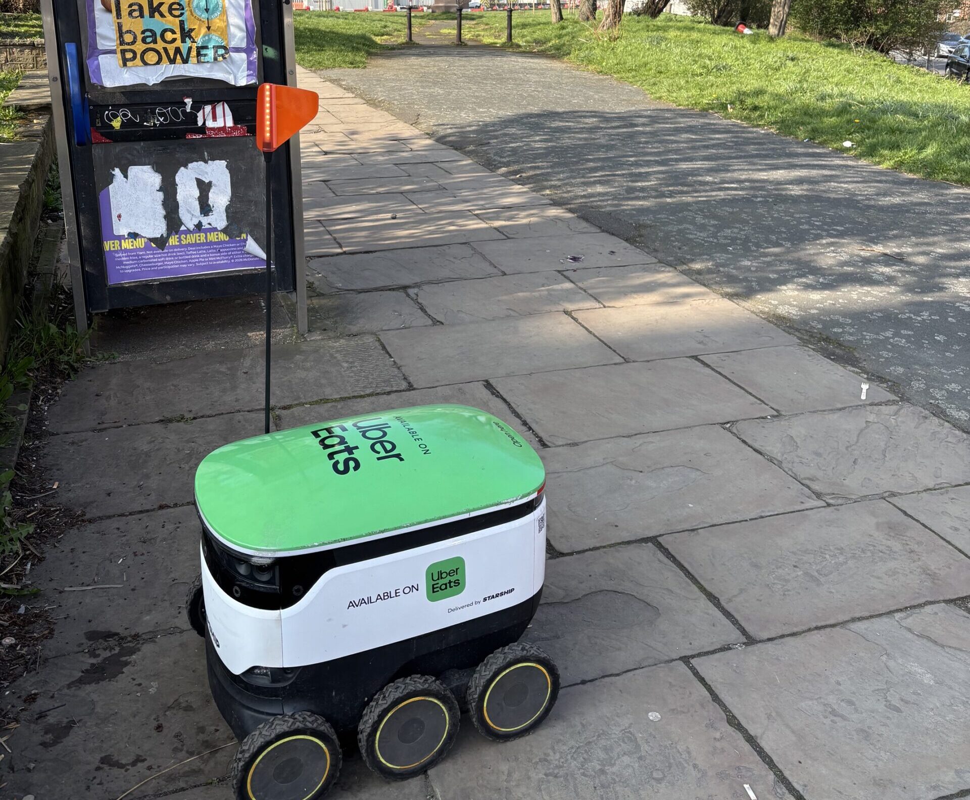 Shows a delivery robot in action on a pavement in Sheffield.