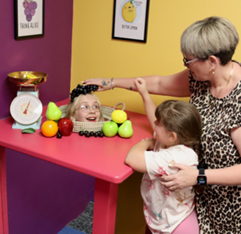 Image of a woman and two young children playing in the gallery
